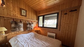 A wooden-paneled room with a bed, a window, and a lamp. - SAPAUDIA G – Ski-in/ski-out apartment, lovely view – Parking (La Clusaz)