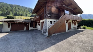 Un chalet in legno con un balcone, una scala in pietra e vista sulle montagne.