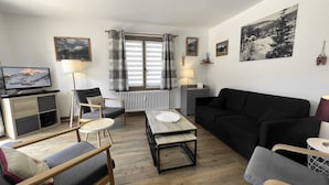 Una sala de estar moderna con un sofá, sillones, una mesa de centro, un televisor y obras de arte en las paredes.