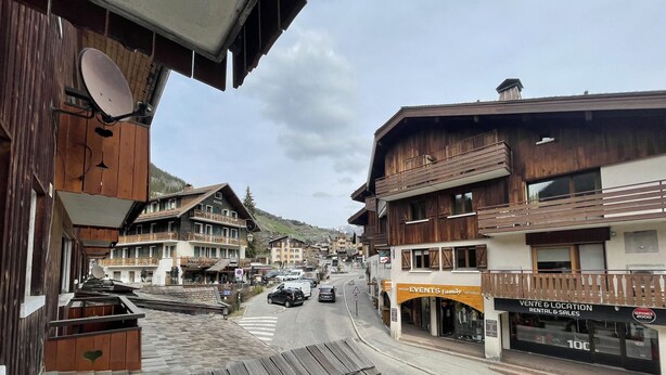 Une vue de rue avec des bâtiments en bois, un hôtel et un magasin de location et de vente.