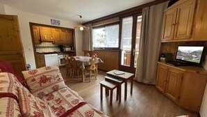 Un salon confortable avec un canapé, une table à manger et des chaises, des meubles en bois et un téléviseur.