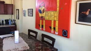 A dining area with a marble table, chairs, a red abstract painting, and a framed picture on the wall. - Deluxe Two-Bedroom Penthouse Apartment in Escalante, San Jose Center (San José)
