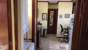 A narrow hallway with a washing machine, a trash bin, a refrigerator, and a chair. - Deluxe Two-Bedroom Penthouse Apartment in Escalante, San Jose Center (San José)