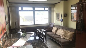 A living room with a sofa, a dining table with chairs, a laptop, and a window with curtains. - Deluxe Two-Bedroom Penthouse Apartment in Escalante, San Jose Center (San José)