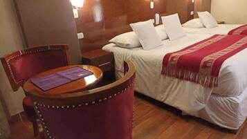 Una habitación de hotel con una cama, una mesita de noche de madera, una silla morada y una pequeña mesita auxiliar.