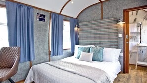 Una camera da letto con un letto, una sedia, un bagno con uno specchio e un cartello appeso al muro.