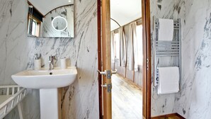 Un bagno con parete in marmo, lavandino, specchio e porta asciugamani.