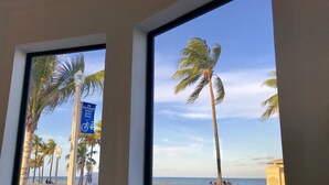 Vista di una spiaggia con palme e un cartello che indica l'accesso consentito solo a mezzi non motorizzati e biciclette.