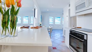 Una cucina moderna con mobili bianchi, un'isola grande e vista sull'esterno.