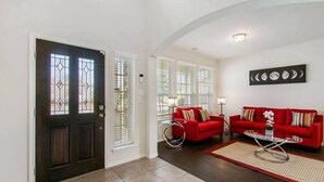 Una sala de estar con dos sofás rojos, una mesita de centro y una puerta con paneles de vidrio emplomado.