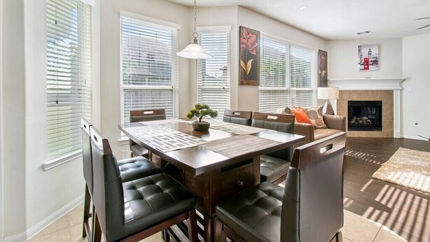 Un comedor con una mesa de madera oscura, sillas de cuero negro y una lámpara colgante.