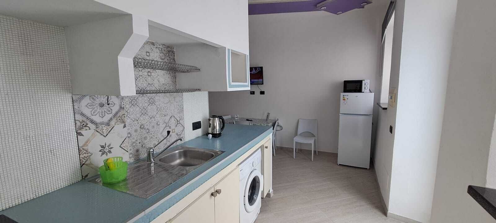Cocina compacta con lavadora, microondas y pileta.