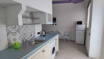 Cocina compacta con lavadora, microondas y pileta.