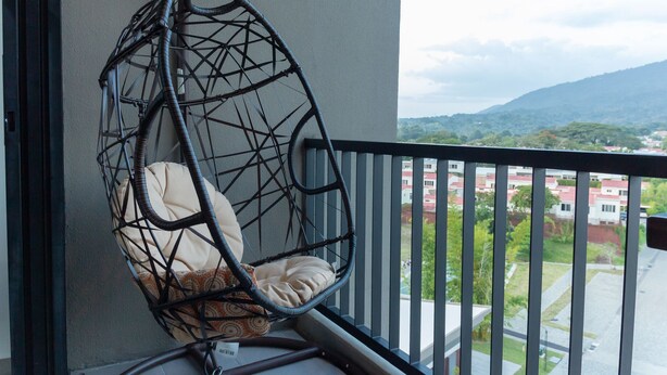 Un balcon avec un fauteuil suspendu et une vue sur un quartier résidentiel.
