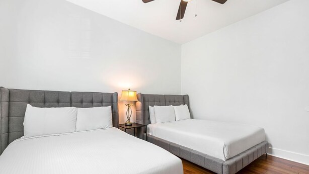 Een hotelkamer met twee bedden, een nachtkastje met een lamp en een houten vloer.