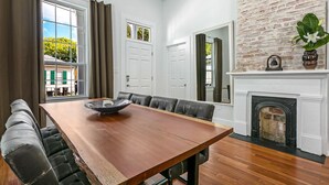 A dining area with a wooden table, black leather chairs, a fireplace, and a brick wall. - 15% OFF Monthly | 10% OFF Weekly-Spacious 5BR Near Magazine St & Uptown (New Orleans)