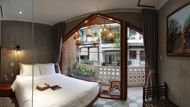Ein Schlafzimmer mit einem großen Bett, einer Holzbalkendecke, einem Balkon mit Pflanzen und einem Bild an der Wand.