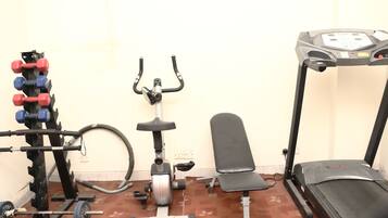 A home gym with a barbell rack, dumbbells, an elliptical, a bench, and a treadmill.