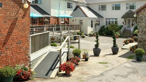 A courtyard with a brick building, a white building with a balcony, and potted plants. - 1 bedroom accommodation in Sidbury, near Sidmouth (Sidbury, near Sidmouth)
