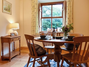 A dining area with a round table, chairs, a lamp, and a window with curtains. - 1 bedroom accommodation in Lindale, near Grange-over-Sands (Lindale, near Grange-over-Sands)