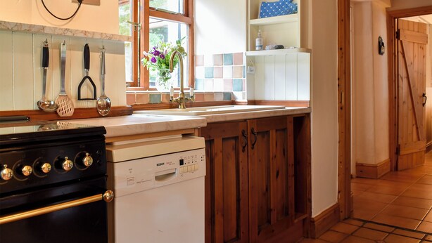 A kitchen with a Bosch dishwasher, wooden cabinets, a window with a view, and a countertop with kitchen utensils. - 1 bedroom accommodation in Lindale, near Grange-over-Sands (Lindale, near Grange-over-Sands)