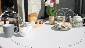 A table set with a coffee maker, teapot, cups, a plate with pastries, a vase with flowers, and a bread loaf. - 1 bedroom accommodation in Lindale, near Grange-over-Sands (Lindale, near Grange-over-Sands)