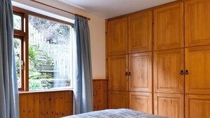 A bedroom with a large bed, wooden wardrobe, and a window with curtains. - 1 bedroom accommodation in Lindale, near Grange-over-Sands (Lindale, near Grange-over-Sands)