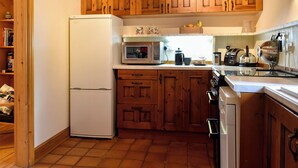 A kitchen with wooden cabinets, a white refrigerator, a microwave, a coffee maker, and a kettle. - 1 bedroom accommodation in Lindale, near Grange-over-Sands (Lindale, near Grange-over-Sands)