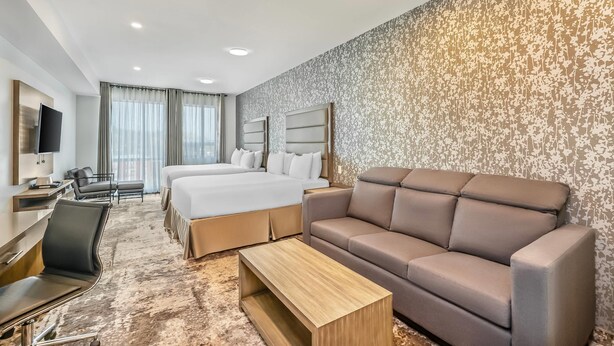 Una habitación de hotel con cama, sofá, escritorio y televisión.