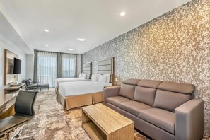 Ein Hotelzimmer mit Bett, Sofa, Schreibtisch und Fernseher.