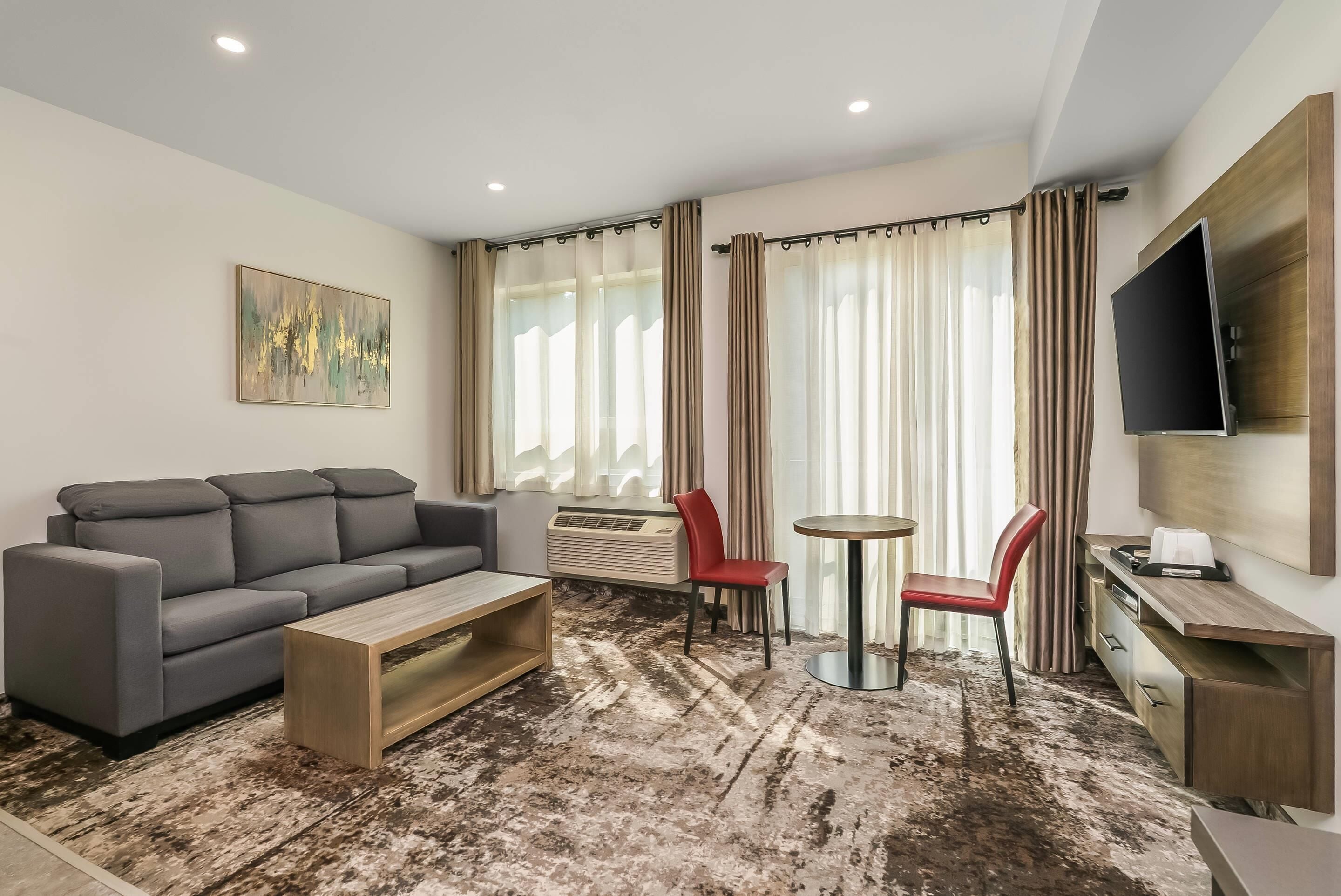 A modern living room with a sofa, a coffee table, a TV, and a small dining area.