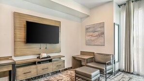 Una habitación moderna con un televisor de pantalla plana montado en una pared de madera, un sofá, una mesita y un ventanal con cortinas.