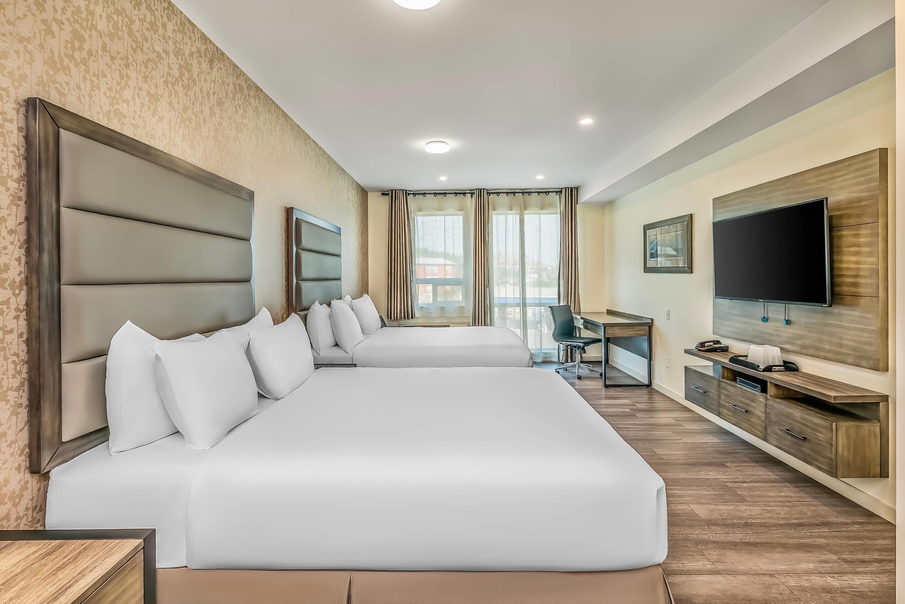 Une chambre d’hôtel avec deux lits, un bureau, une télévision et une vue sur la ville.
