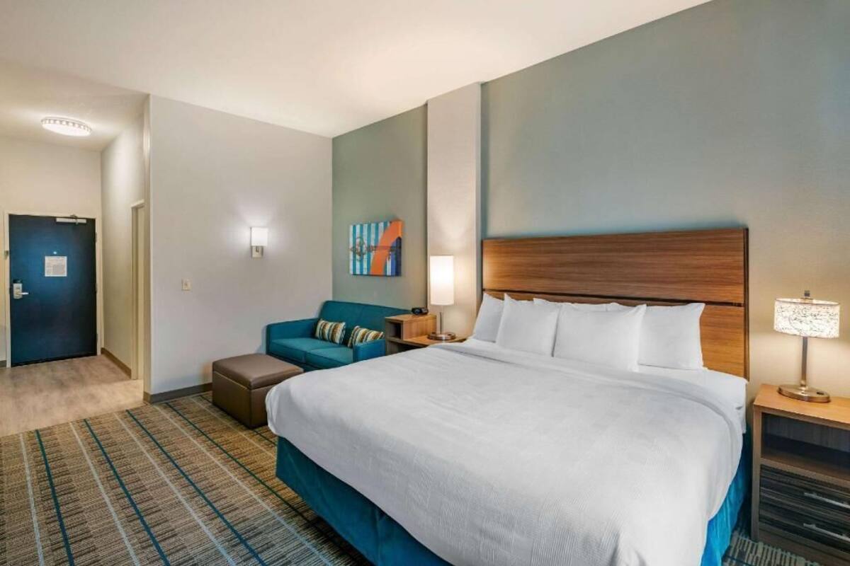 A hotel room with a large bed, a sofa, a desk, and a lamp.