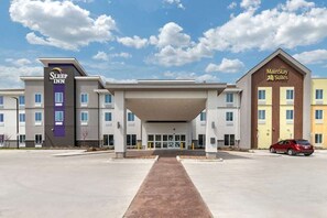 A hotel with a central entrance, Sleep Inn and MainStay Suites signs, and a clear sky. - MainStay Suites Spokane Airport (Spokane)
