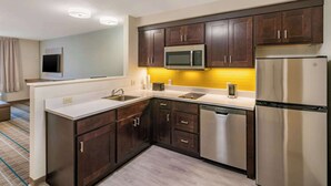 A modern kitchen with dark wooden cabinets, stainless steel appliances, and a white countertop. - MainStay Suites Spokane Airport (Spokane)