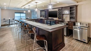 A modern kitchen with a central island, bar stools, stainless steel appliances, and a large window providing natural light. - MainStay Suites Spokane Airport (Spokane)