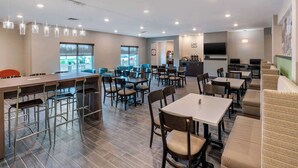 A modern hotel lobby with a bar area, dining tables, and comfortable seating. - MainStay Suites Spokane Airport (Spokane)