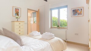 Een slaapkamer met een bed, een kaptafel, een raam met uitzicht en twee ingelijste foto's aan de muur.