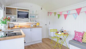Une cuisine compacte avec des meubles blancs, un plan de travail en bois, une chaise jaune et une petite table à manger.