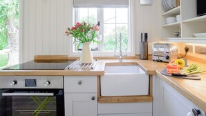 Une cuisine avec un évier blanc, un grille-pain et un vase rempli de fleurs.