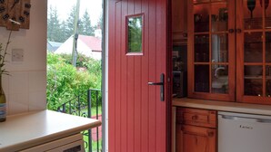 Une cuisine avec une porte rouge, des placards en bois et une fenêtre donnant sur un jardin.