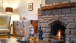 Un salon chaleureux avec une cheminée en pierre, un meuble en bois et une table sur laquelle se trouvent des verres et une bouteille.