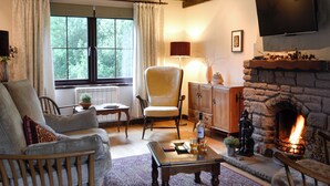 Un salon chaleureux avec une cheminée, un canapé confortable, une table basse en bois et un téléviseur fixé au mur.