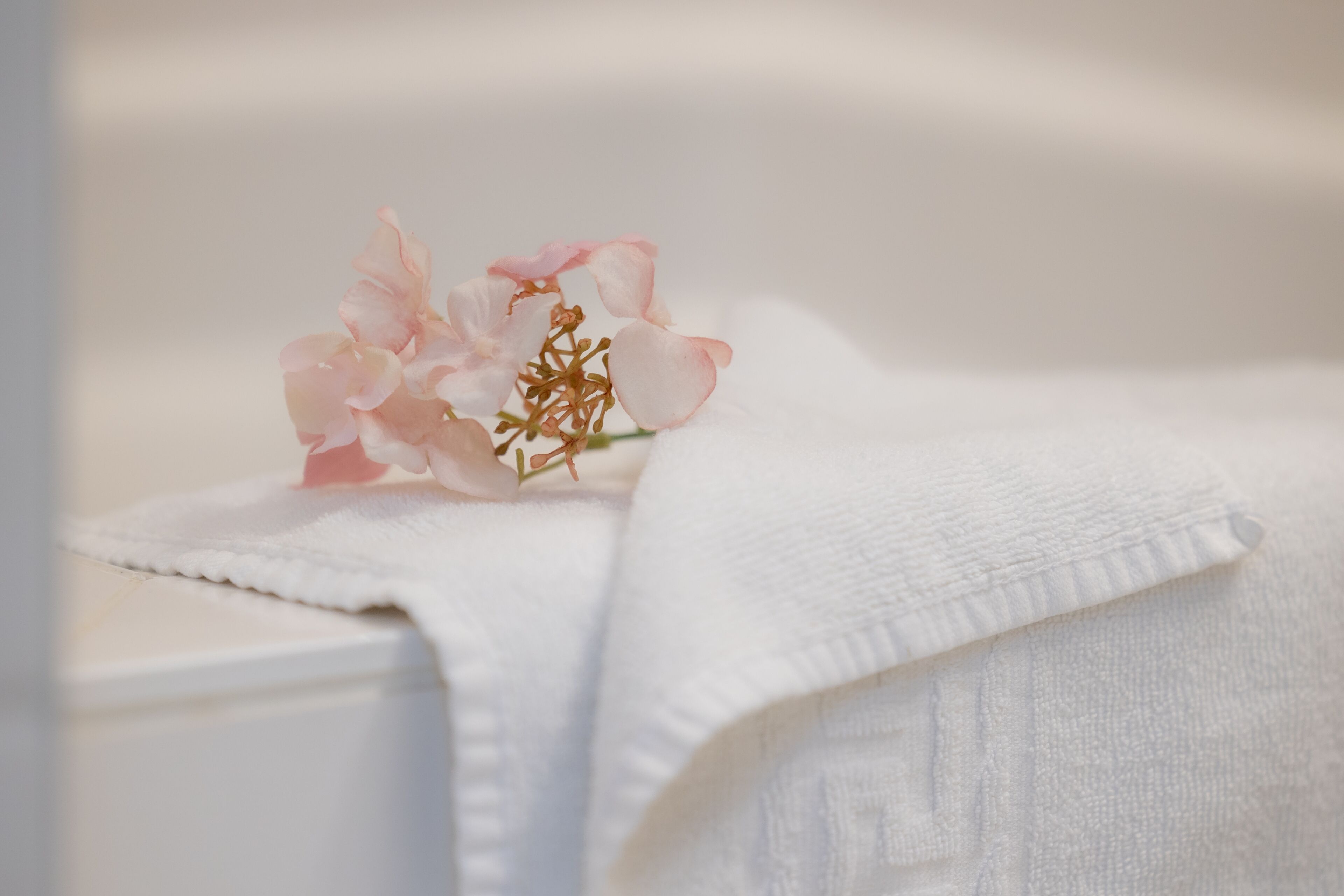 A white towel with a pink flower on it.