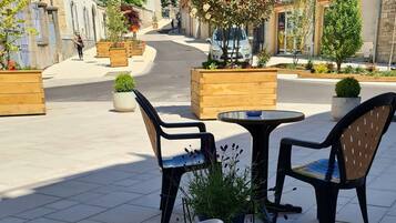 An outdoor café with tables, chairs, and a variety of food and drink items.