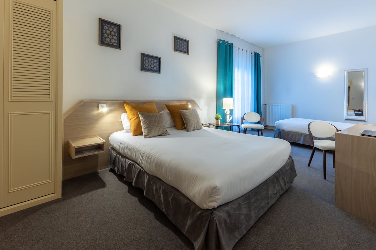 Ein Hotelzimmer mit einem großen Bett, Nachttischen, einem Schreibtisch und einem Sessel.