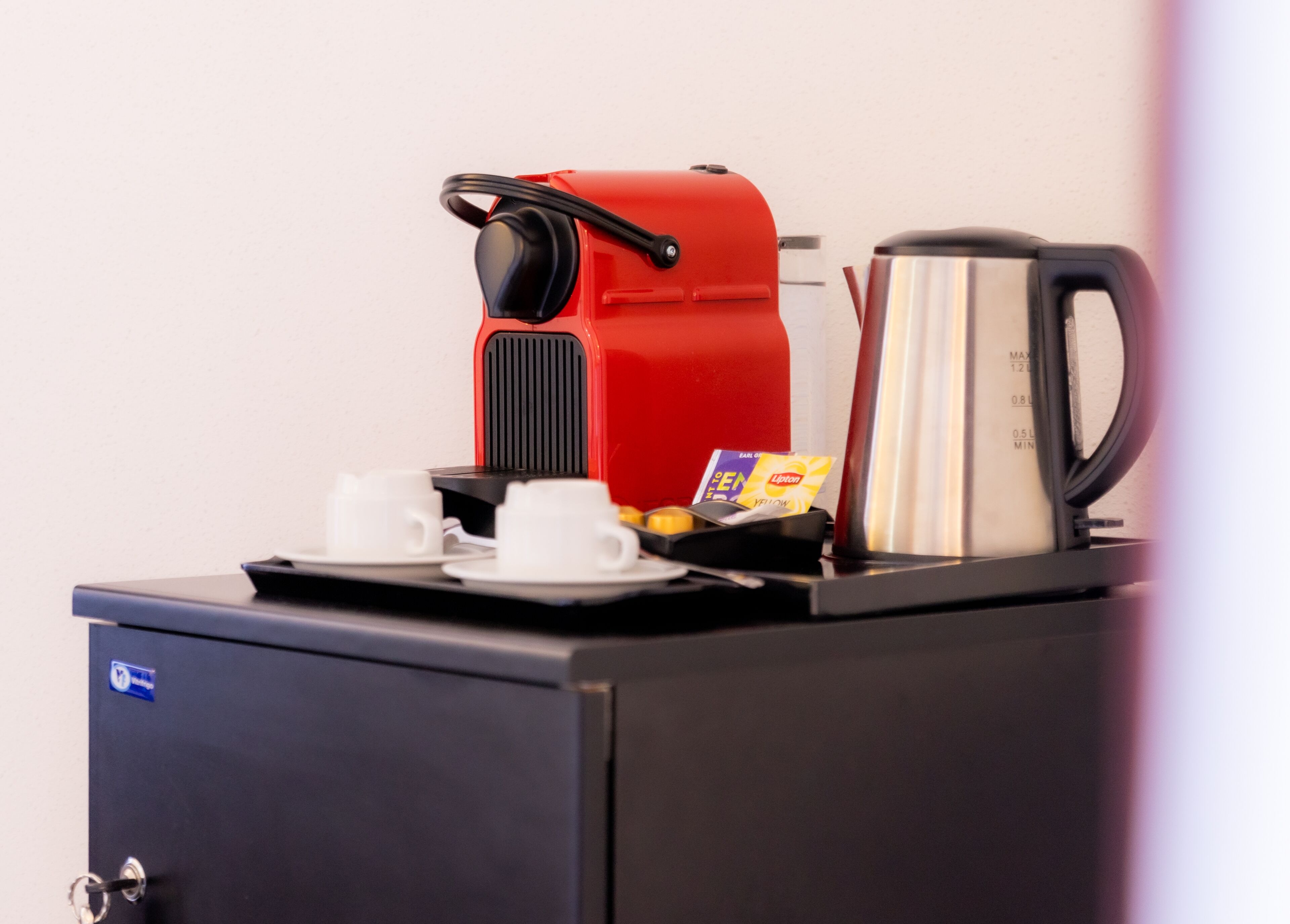 A coffee machine with two cups and a card on a tray.