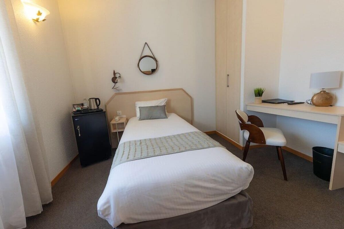 Ein Hotelzimmer mit Bett, Schreibtisch, Stuhl und einem kleinen Schrank.