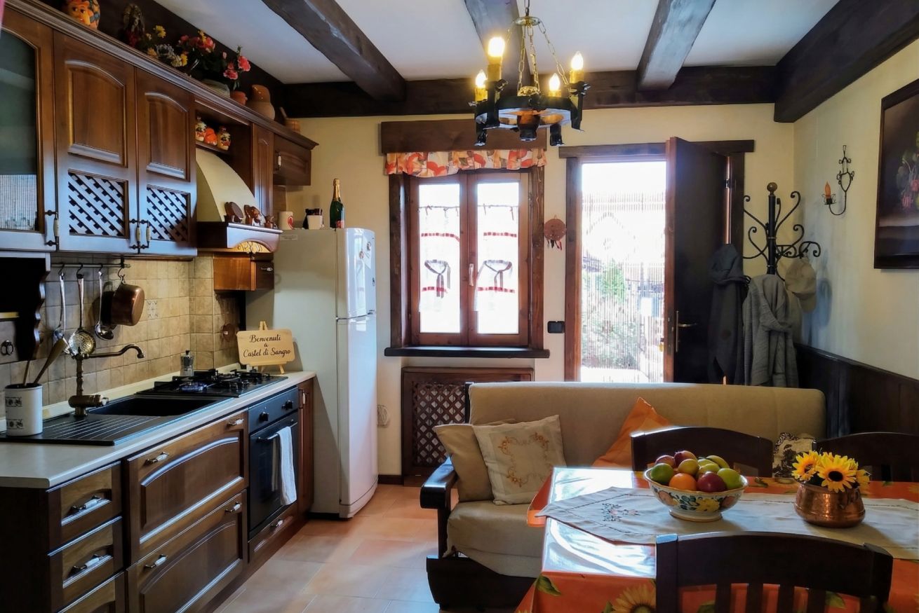 A kitchen with wooden cabinets, a dining area with a table set for two, and a window with a view of the outside.